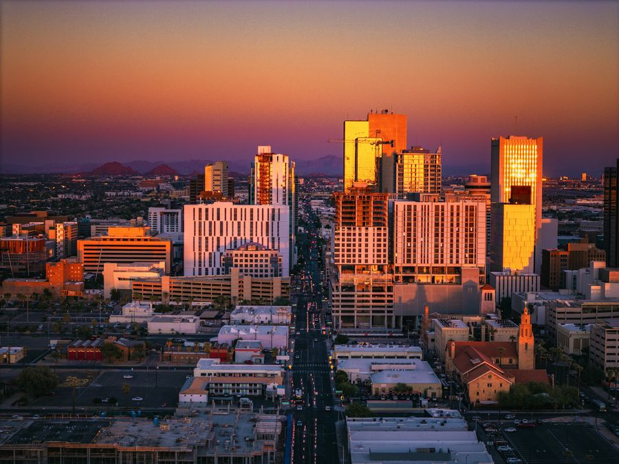 Downtown Phoenix skyline glowing at golden hour with mountains in the distance